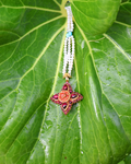 Decorative necklace with a star-shaped pendant on a green leaf
