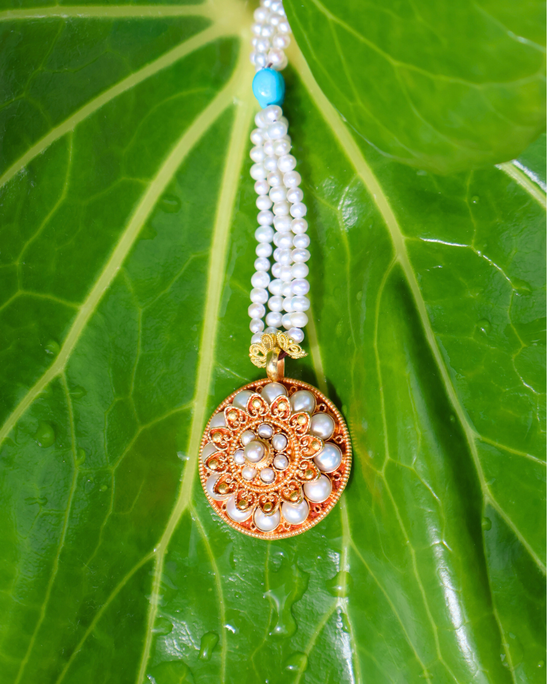 Decorative necklace with a pendant on a green leaf