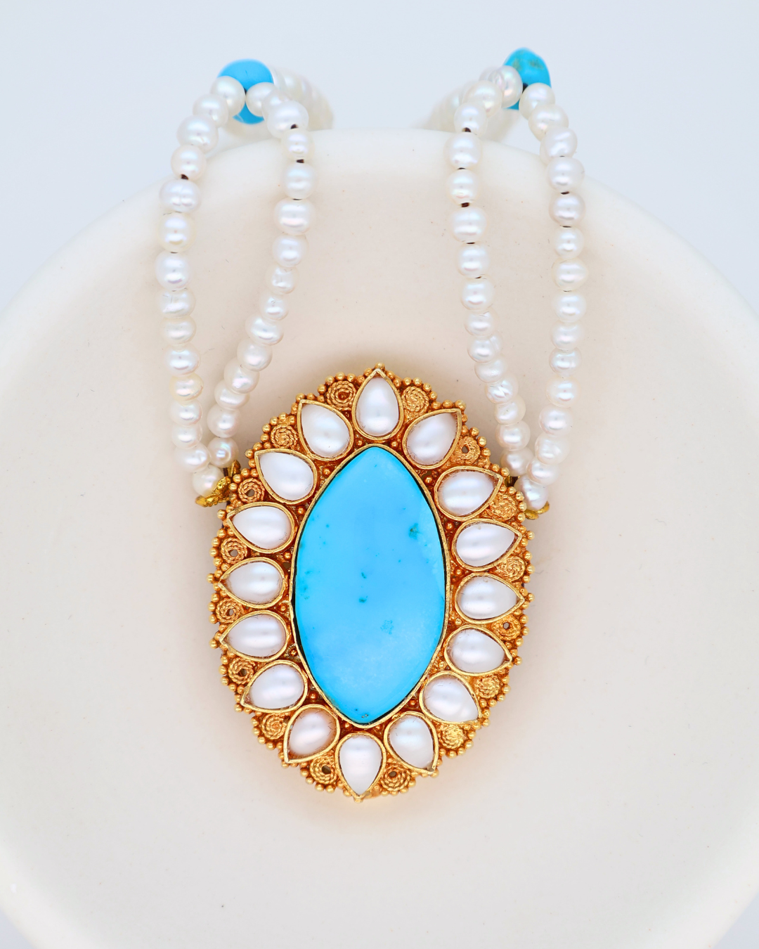 Pearl necklace with a blue pendant on a white background