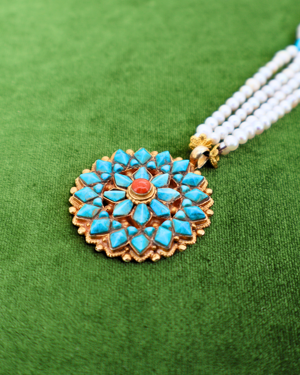 Decorative pendant with turquoise stones and gold accents on a green background