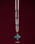 Necklace with white beads, turquoise stones, and a star-shaped pendant on a dark red background.