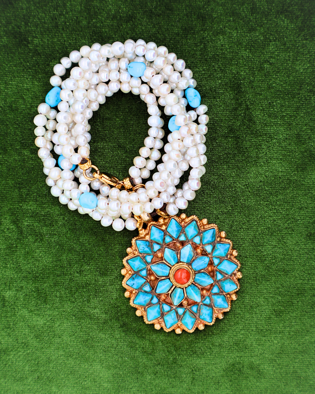 Pearl necklace with a blue and gold pendant on a green background