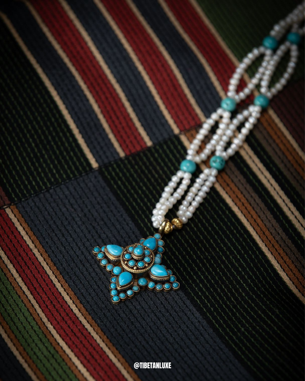 Necklace with turquoise pendant on a striped fabric background