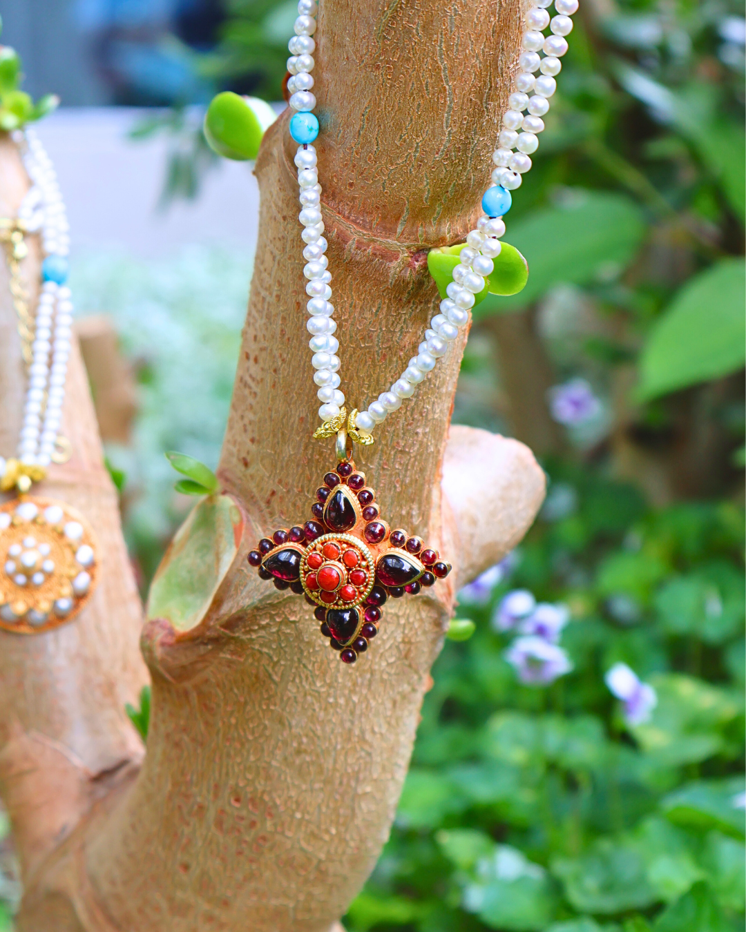Decorative necklace with a star-shaped pendant on a wooden branch with green leaves in the background