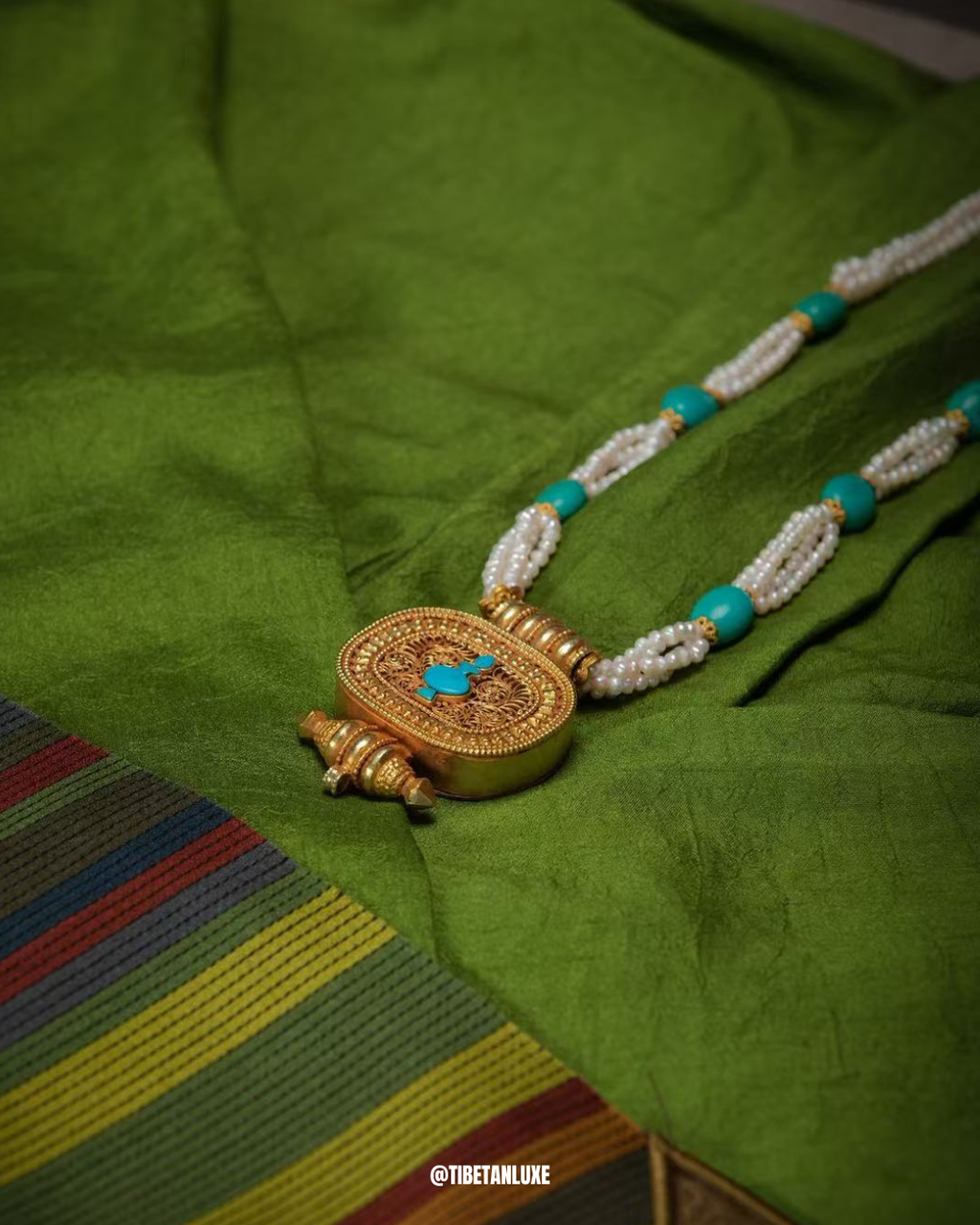 Gold necklace with turquoise stones on a green fabric background